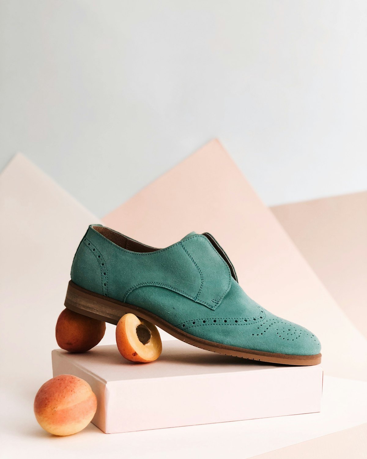 Green suede shoe on a pastel set with peaches