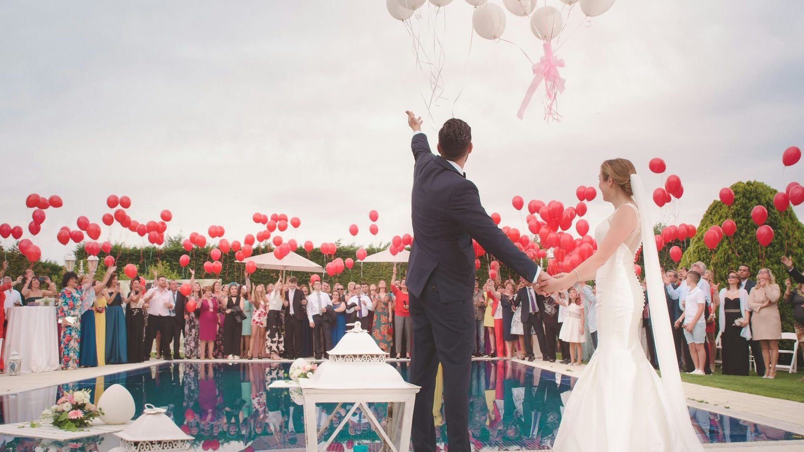 Bride and groom at an outdoor wedding with red balloons