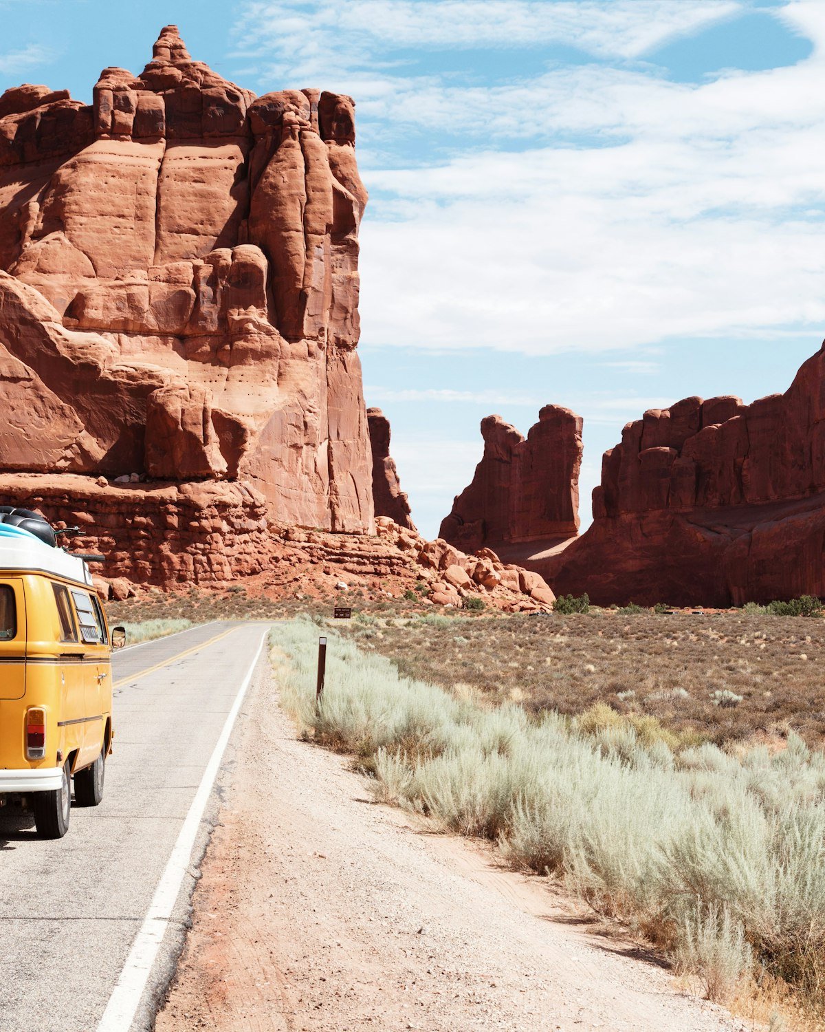 Yellow van on a desert road between red rocks