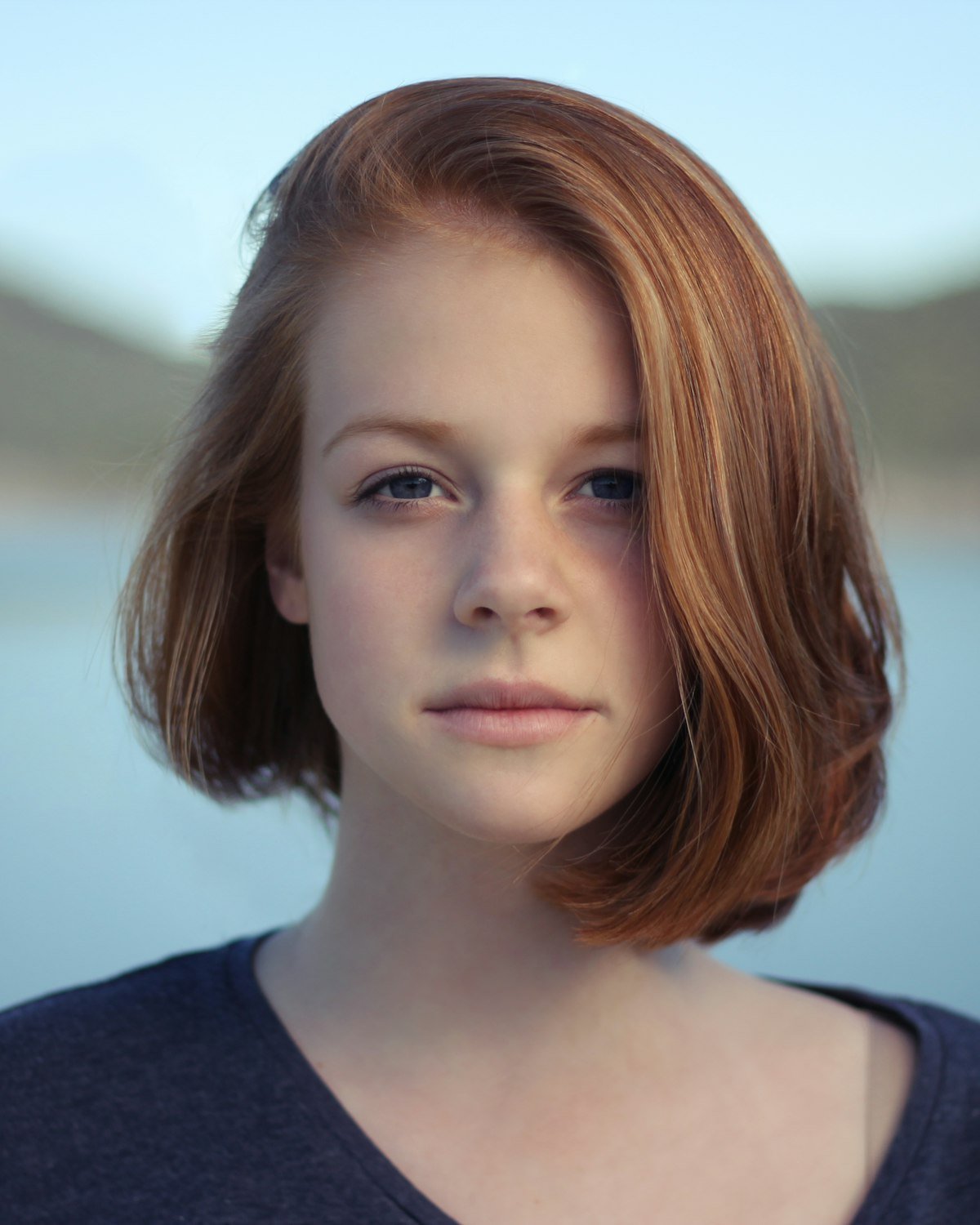 Woman with short red hair by a lake